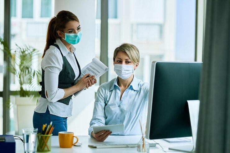 female-business-colleagues-with-face-masks-working-office-reading-email-computer
